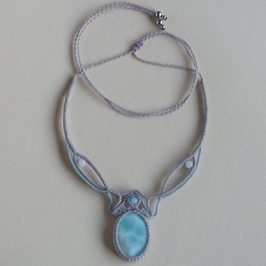 Necklace in taupe gray/frosted blue micro-macramé with a natural gemstone in soft shades of white and light blue in the center.