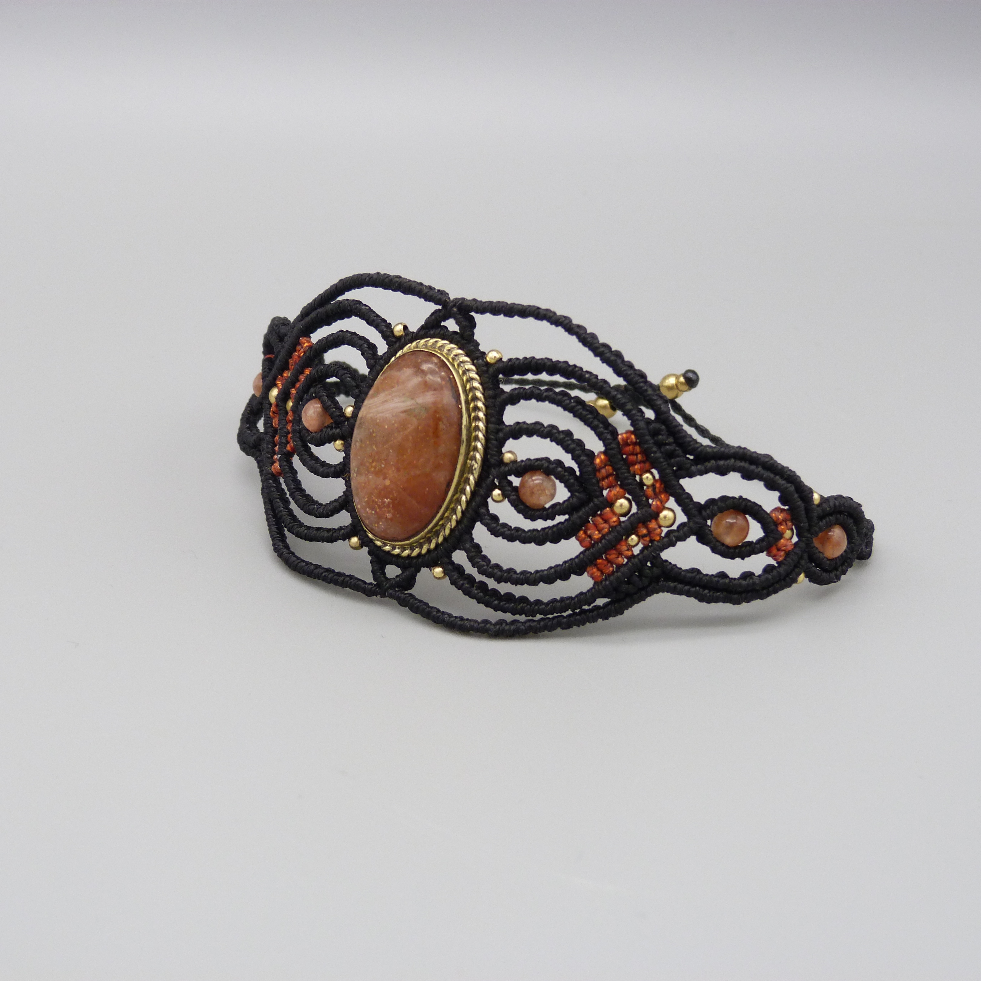 Manchette noire en micro-macramé avec une pierre de soleil