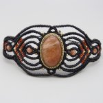 Manchette noire en micro-macramé avec une pierre de soleil