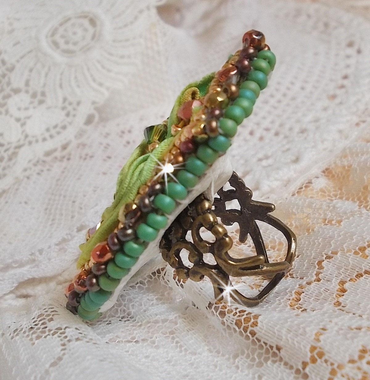 Venetian moon ring embroidered with a chameleon colored silk ribbon, Swarovski crystals, various pearls and seed beads