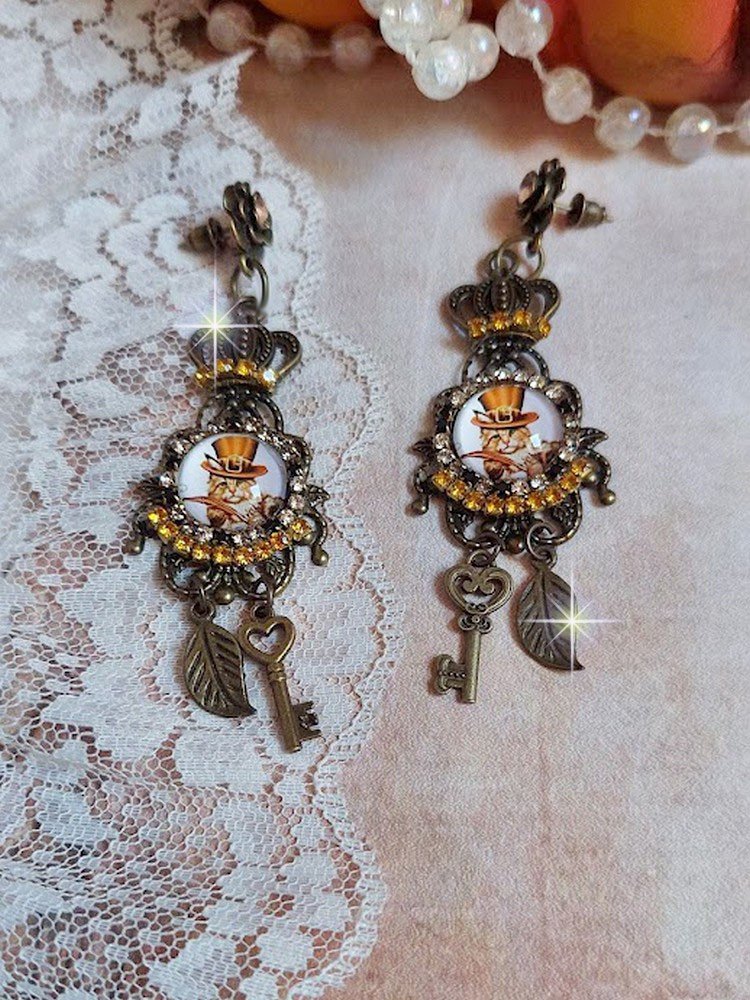 BO Chatibo Steampunk montées avec cabochons ronds en verre représentant un chat chapeauté Haute de Forme Orange. Strassées avec une couronne, breloques clés et feuilles. Montées sur clips Bronze