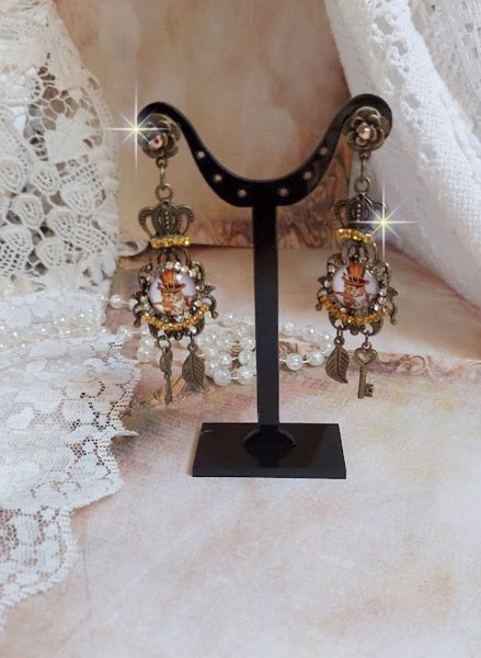 BO Chatibo Steampunk mont&eacute;es avec cabochons ronds en verre repr&eacute;sentant un chat chapeaut&eacute; Haute de Forme Orange. Strass&eacute;es avec une couronne, breloques cl&eacute;s et feuilles. Mont&eacute;es sur clips Bronze