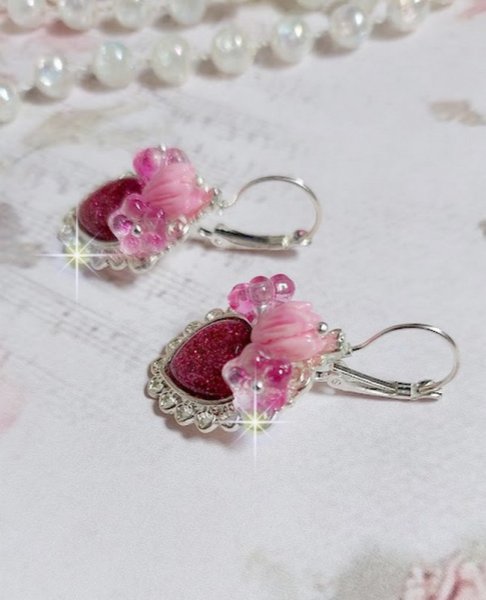 BO C&oelig;ur Ardent mont&eacute;es avec des dormeuses argent&eacute;es &agrave; laquelle s&rsquo;ajoute des c&oelig;urs paillet&eacute;s en r&eacute;sine Fuchsia. Ils sont orn&eacute;s d&rsquo;un bouquet de fleurs en verre &agrave; la couleur Rose pour un style romantique