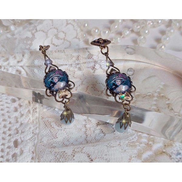 BO Dame au chapeau fleuri repr&eacute;sentant une femme au chapeau entour&eacute; d&rsquo;un ruban noir est mont&eacute; sur des estampes avec des n&oelig;uds en cristal. Une belle &eacute;l&eacute;gance avec ces gouttes en Jade teint&eacute;es de Bleu