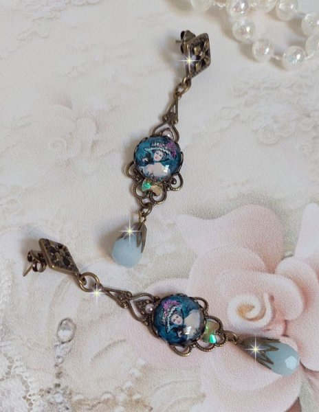 BO Dame au chapeau fleuri repr&eacute;sentant une femme au chapeau entour&eacute; d&rsquo;un ruban noir est mont&eacute; sur des estampes avec des n&oelig;uds en cristal. Une belle &eacute;l&eacute;gance avec ces gouttes en Jade teint&eacute;es de Bleu