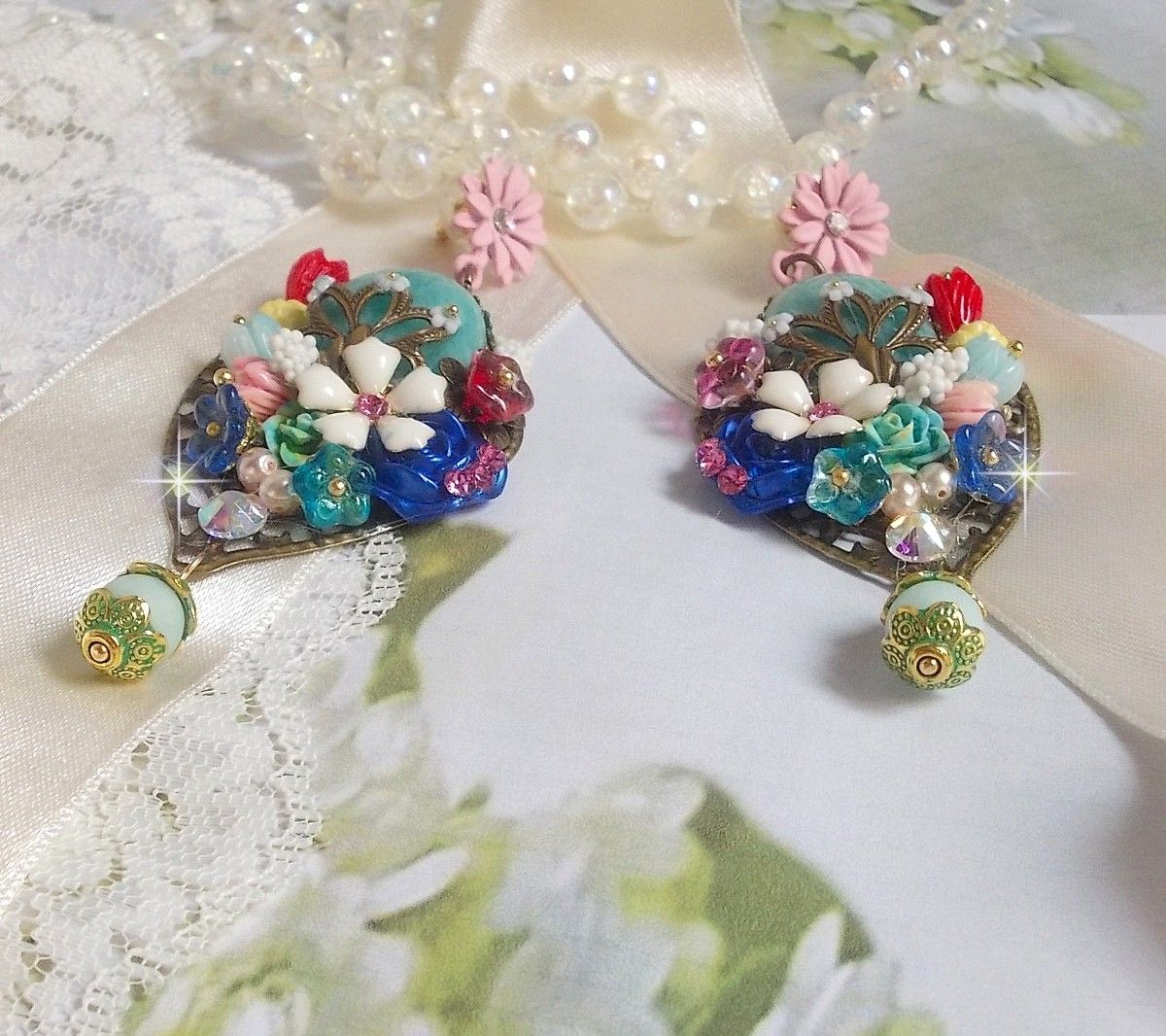 BO Majestueuses sur des estampes gouttes avec des cabochons aux fleurs vert, or, jaune, rouge, ivoire, cristal, rose et blanc. Les cristaux accompagnent l’ensemble des cabochons et perles en Amazonite