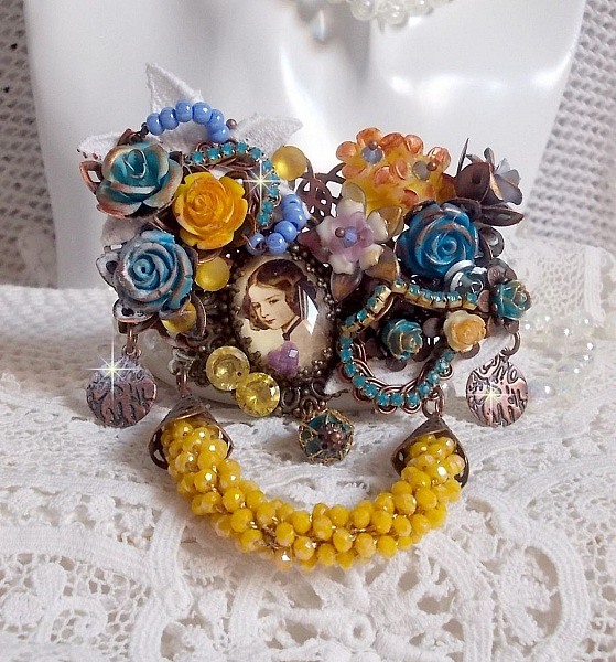 Broche baroque artisanale ornée de fleurs et perles jaunes.