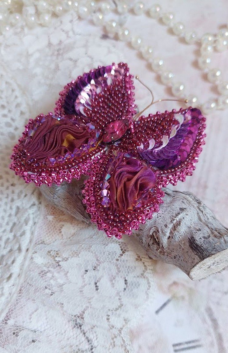 Broche Papillon Violine Fuchsia brodée avec un ruban de soie Fuchsia, Rose et Bordeaux à laquelle s’ajoute une navette sertie, des toupies en Cristal de Swarovski, sequins pailletés et rocailles