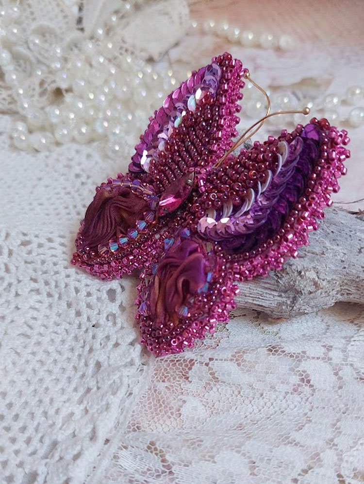 Broche Papillon Violine Fuchsia brodée avec un ruban de soie Fuchsia, Rose et Bordeaux à laquelle s’ajoute une navette sertie, des toupies en Cristal de Swarovski, sequins pailletés et rocailles