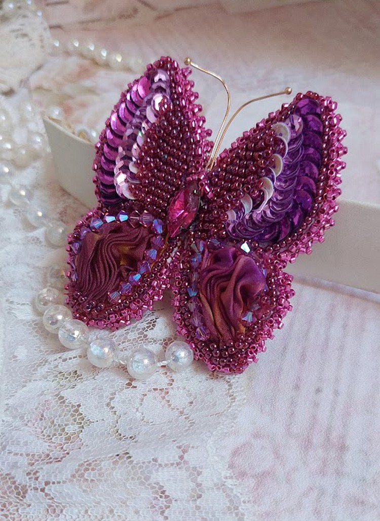 Broche Papillon Violine Fuchsia brodée avec un ruban de soie Fuchsia, Rose et Bordeaux à laquelle s’ajoute une navette sertie, des toupies en Cristal de Swarovski, sequins pailletés et rocailles