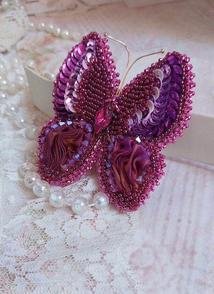 Broche Papillon Violine Fuchsia brodée avec un ruban de soie Fuchsia, Rose et Bordeaux à laquelle s’ajoute une navette sertie, des toupies en Cristal de Swarovski, sequins pailletés et rocailles