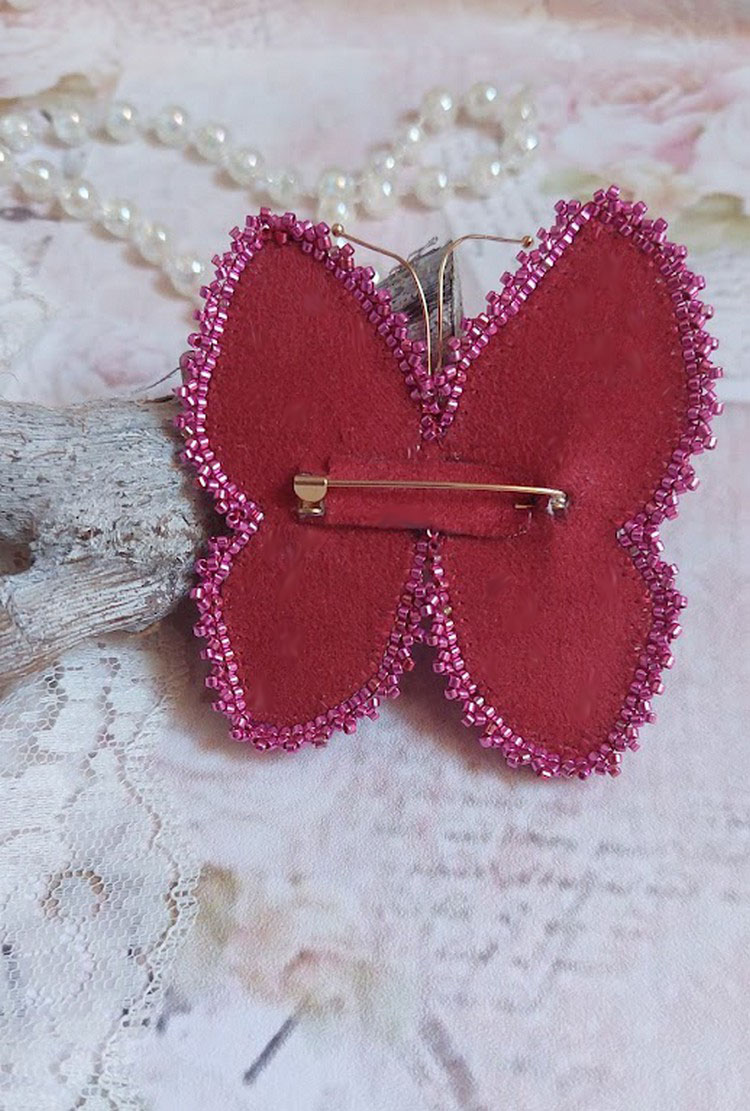 Broche Papillon Violine Fuchsia brodée avec un ruban de soie Fuchsia, Rose et Bordeaux à laquelle s’ajoute une navette sertie, des toupies en Cristal de Swarovski, sequins pailletés et rocailles