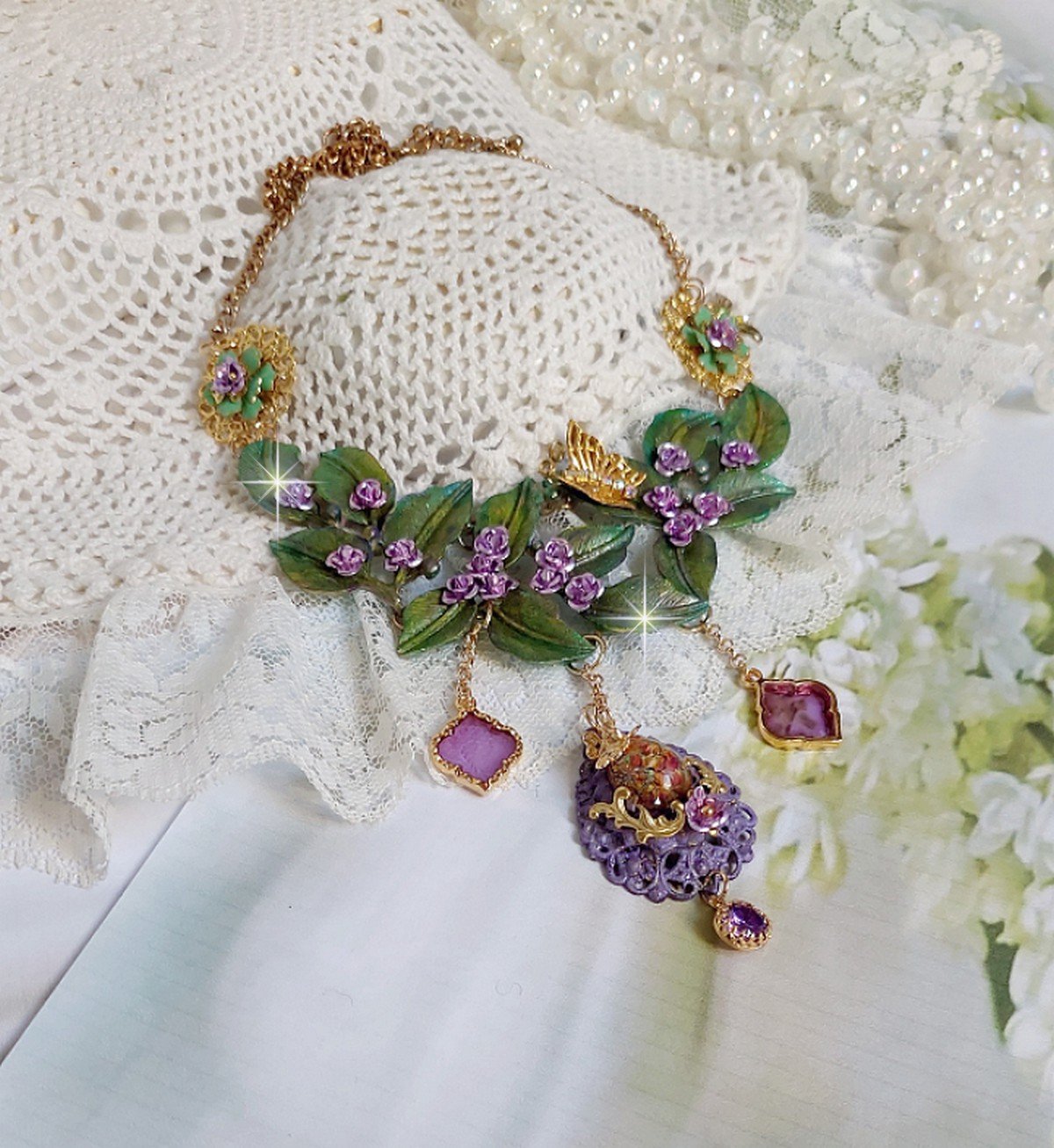 Collier Cam&eacute;lia Japonica mont&eacute; avec un motif feuilles aquarell&eacute;s &agrave; la main, paillettes, breloques papillons et abeille, roses m&eacute;tal, cabochon cristal, pendentifs &eacute;poxy aux couleurs d&rsquo;arc en ciel