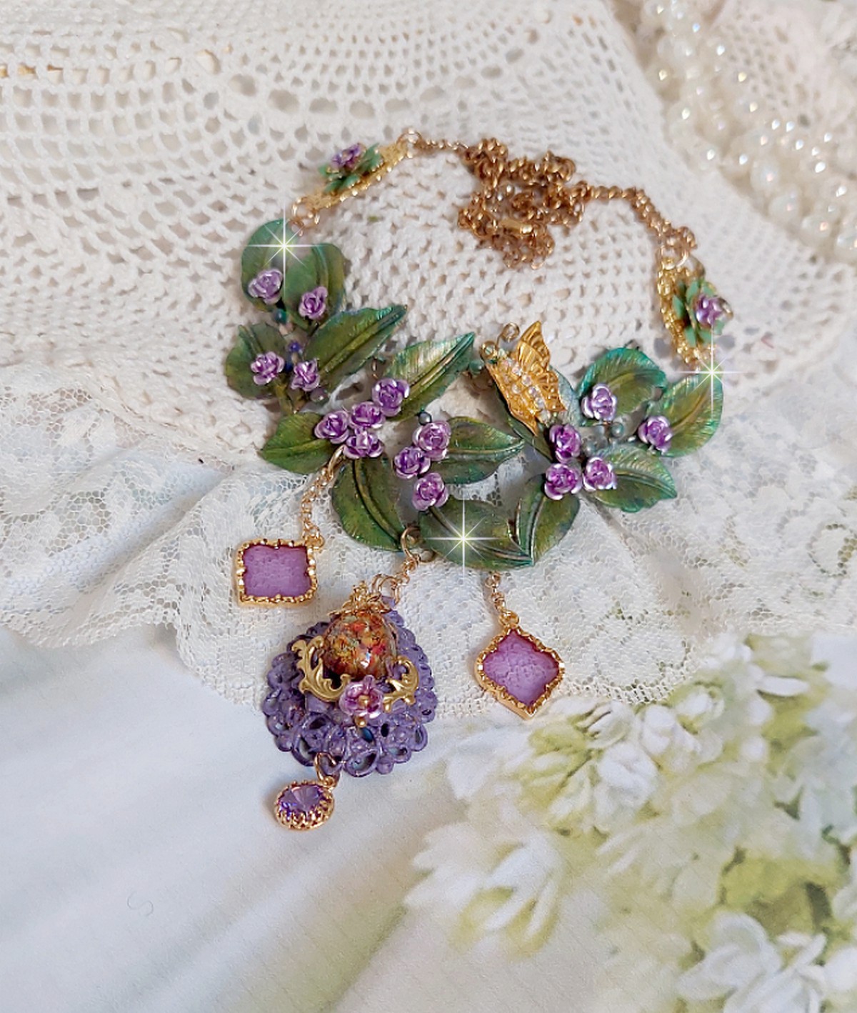 Collier Camélia Japonica monté avec un motif feuilles aquarellés à la main, paillettes, breloques papillons et abeille, roses métal, cabochon cristal, pendentifs époxy aux couleurs d’arc en ciel