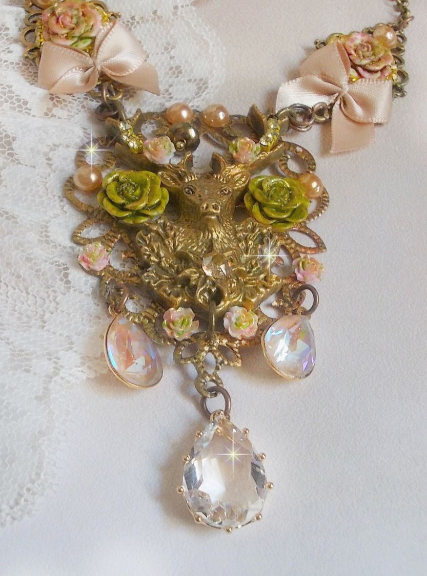 Collier Cerf Fleuri crée avec des cristaux de Swarovski, cabochons en résine, perles en verre, tête de cerf avec bois en métal, pendentif larme en zircon, nœuds en satin et accessoires en laiton 