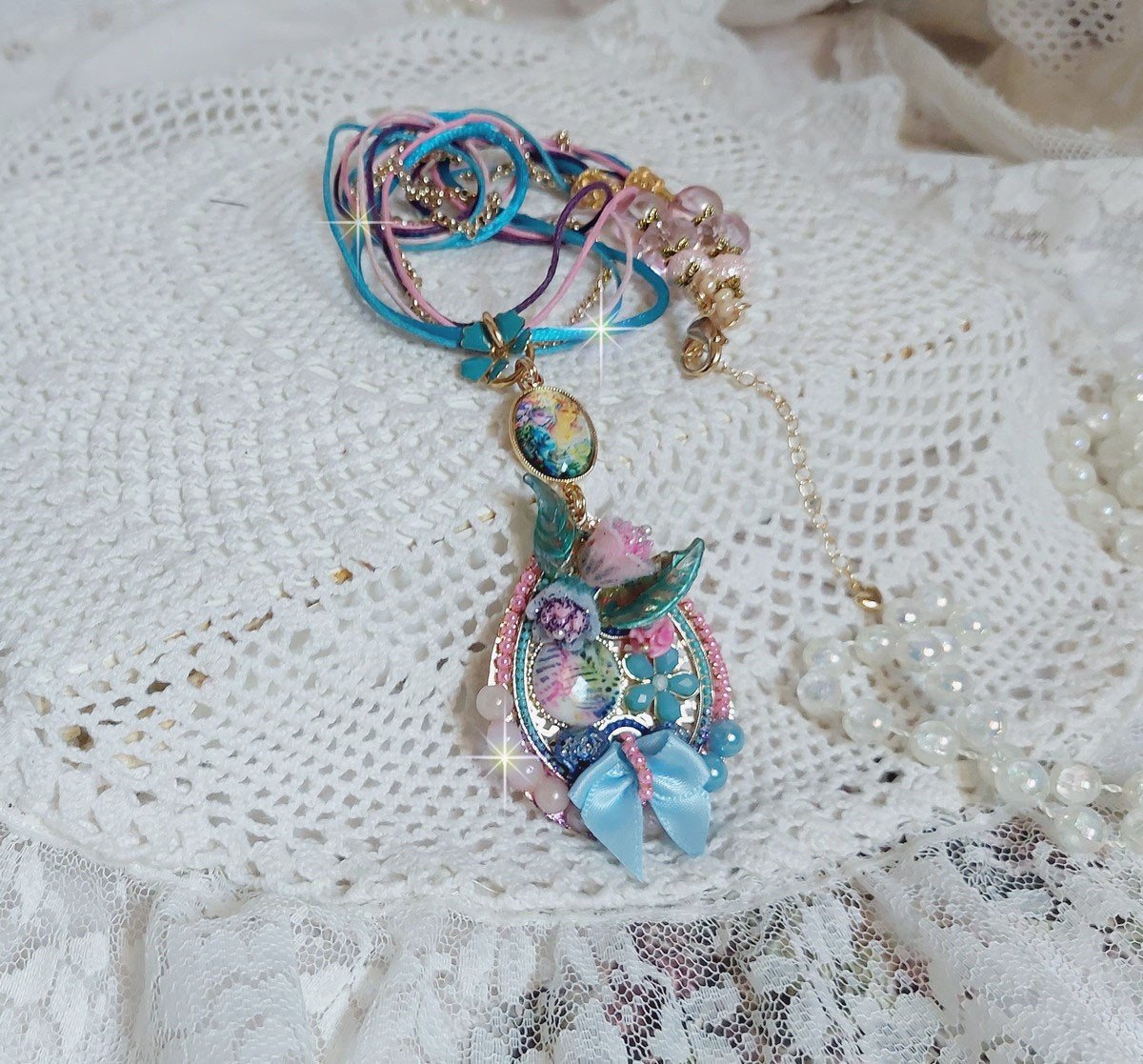  Collier Coquette créé avec deux estampes à laquelle s’ajoute des fleurs en velours floqué, perles aplaties Cristal, fleurs : Epoxy, Porcelaine, Résine, cabochon loupe, rubans et chaîne plaqué Or