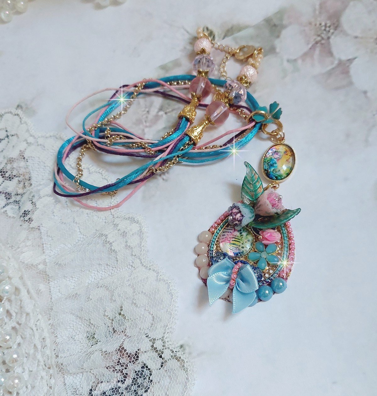  Collier Coquette créé avec deux estampes à laquelle s’ajoute des fleurs en velours floqué, perles aplaties Cristal, fleurs : Epoxy, Porcelaine, Résine, cabochon loupe, rubans et chaîne plaqué Or