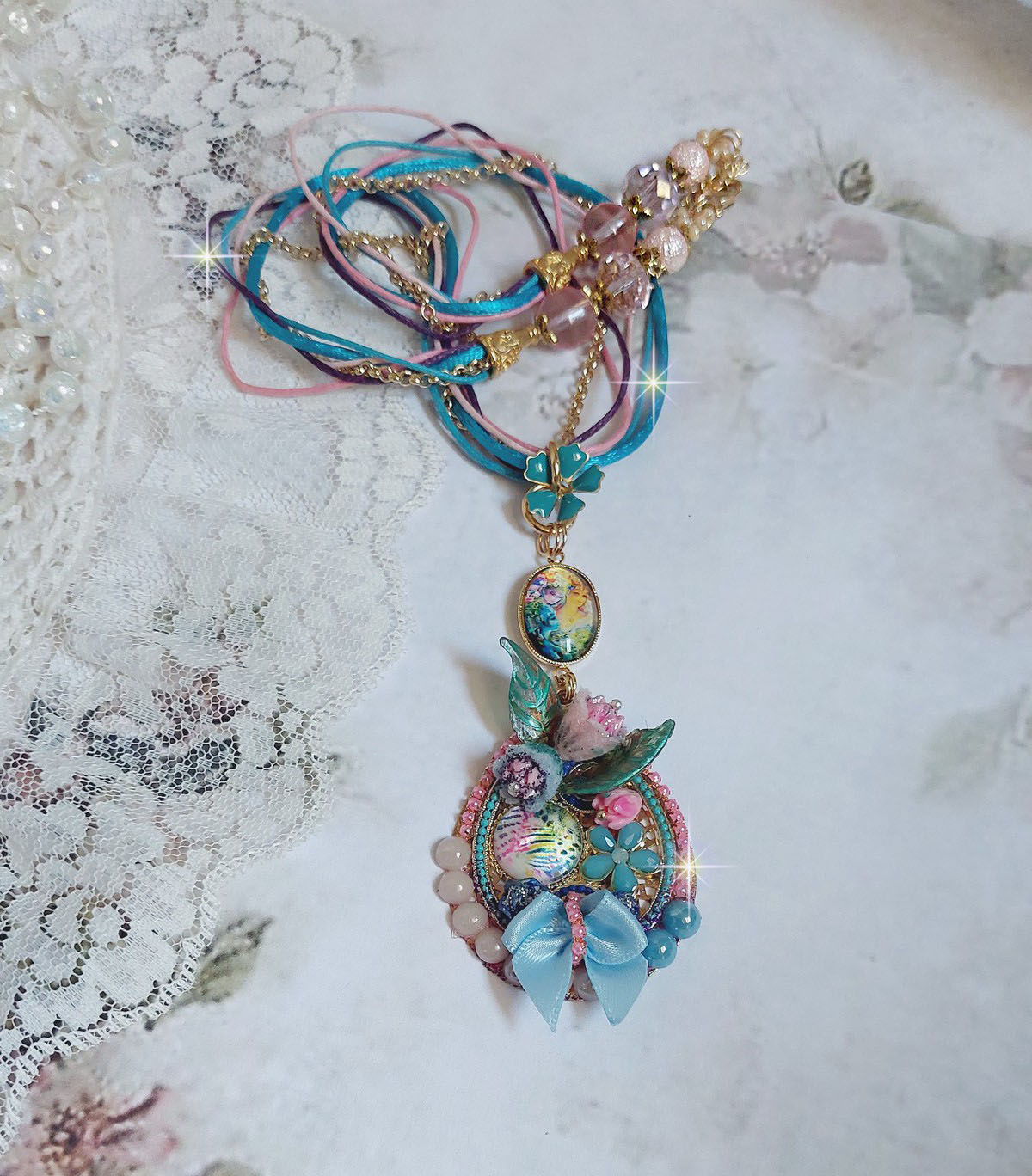  Collier Coquette créé avec deux estampes à laquelle s’ajoute des fleurs en velours floqué, perles aplaties Cristal, fleurs : Epoxy, Porcelaine, Résine, cabochon loupe, rubans et chaîne plaqué Or