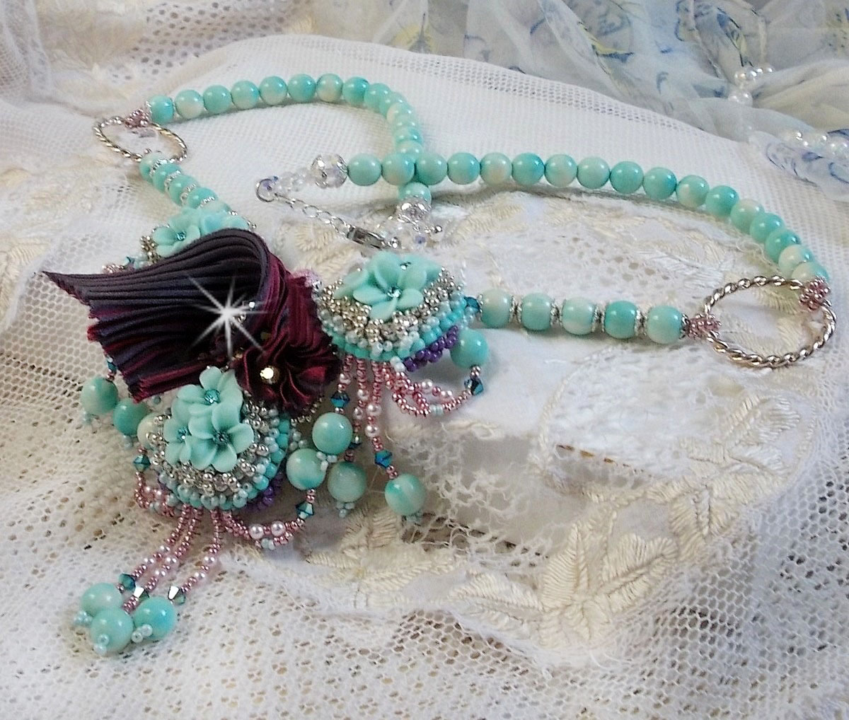 Blue Flowers Haute-Couture necklace embroidered with Swarovski crystals, a silk ribbon in Truffle/Raspberry color and seed beads