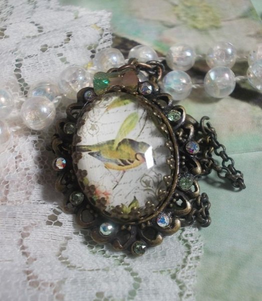 Bird of the Gardens necklace created with a magnifying glass cabochon and crystals mounted on bronze accessories