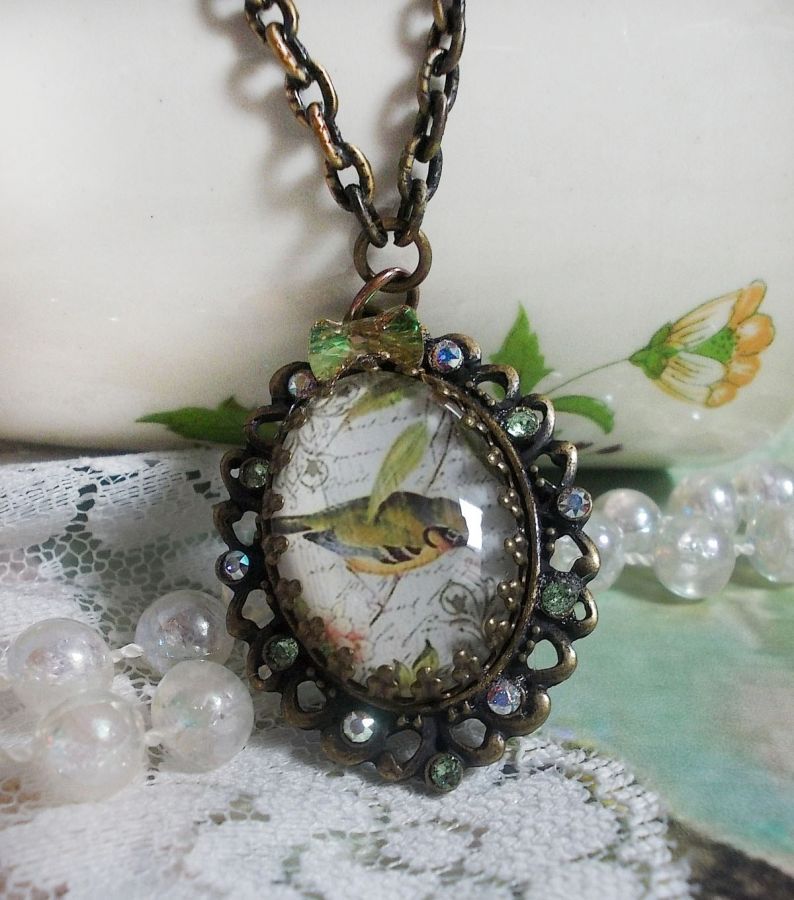 Bird of the Gardens necklace created with a magnifying glass cabochon and crystals mounted on bronze accessories