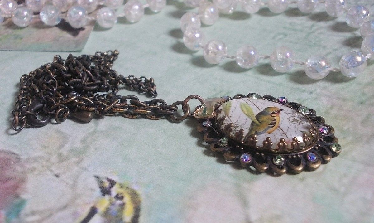 Bird of the Gardens necklace created with a magnifying glass cabochon and crystals mounted on bronze accessories