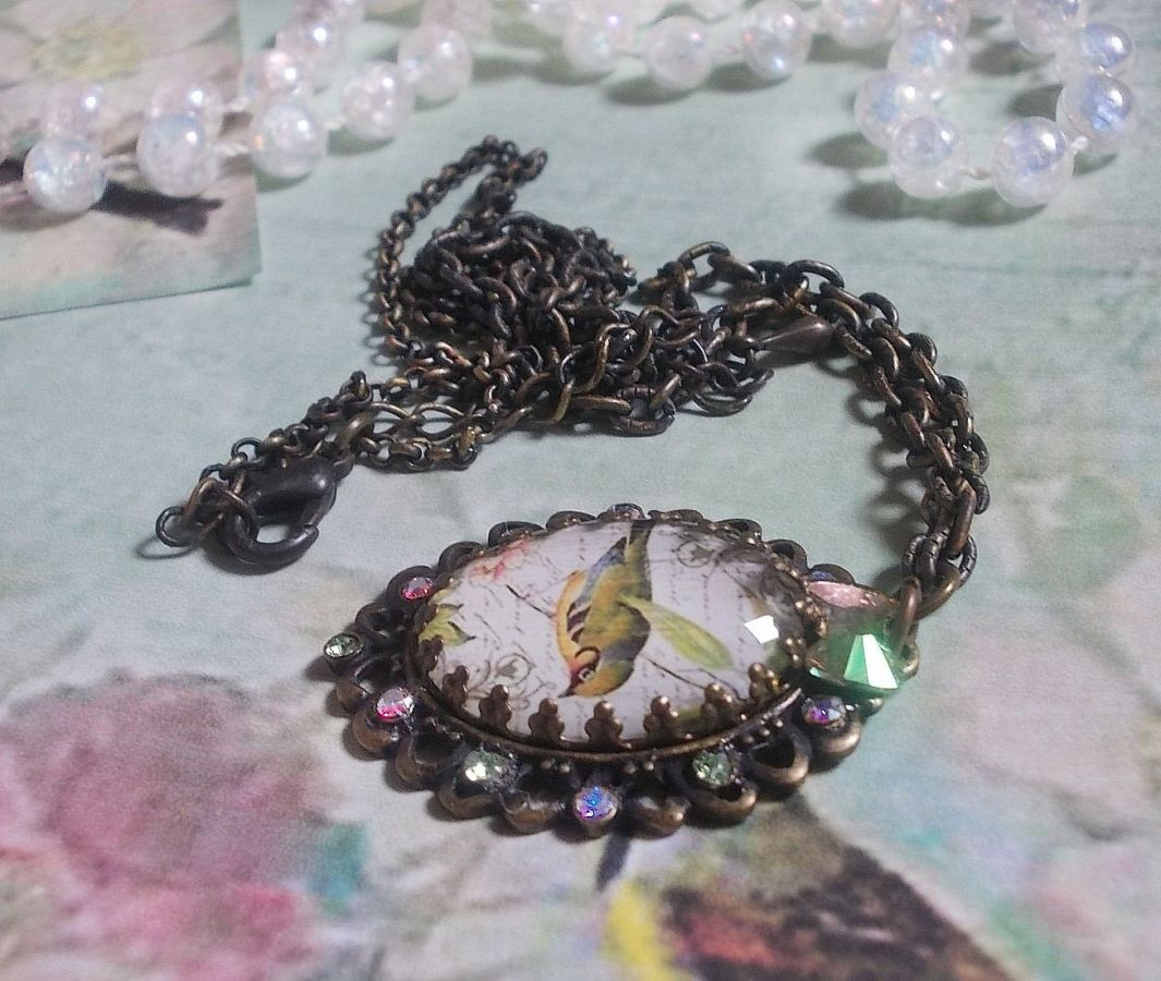 Bird of the Gardens necklace created with a magnifying glass cabochon and crystals mounted on bronze accessories