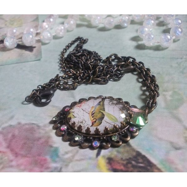 Bird of the Gardens necklace created with a magnifying glass cabochon and crystals mounted on bronze accessories