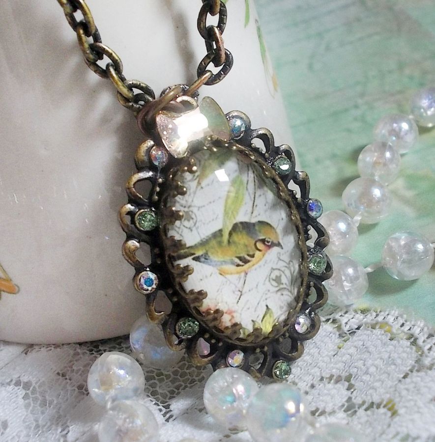 Bird of the Gardens necklace created with a magnifying glass cabochon and crystals mounted on bronze accessories