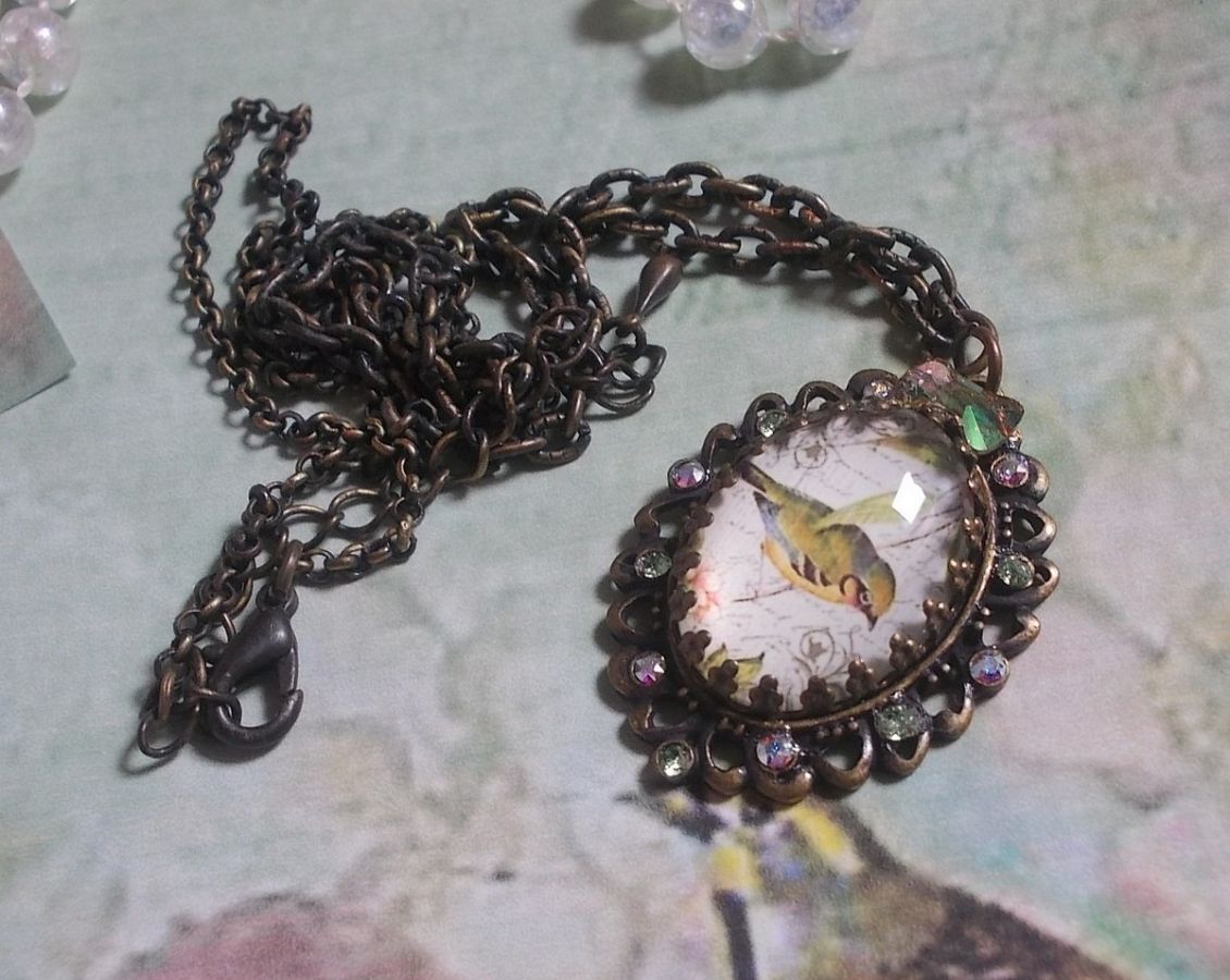 Bird of the Gardens necklace created with a magnifying glass cabochon and crystals mounted on bronze accessories