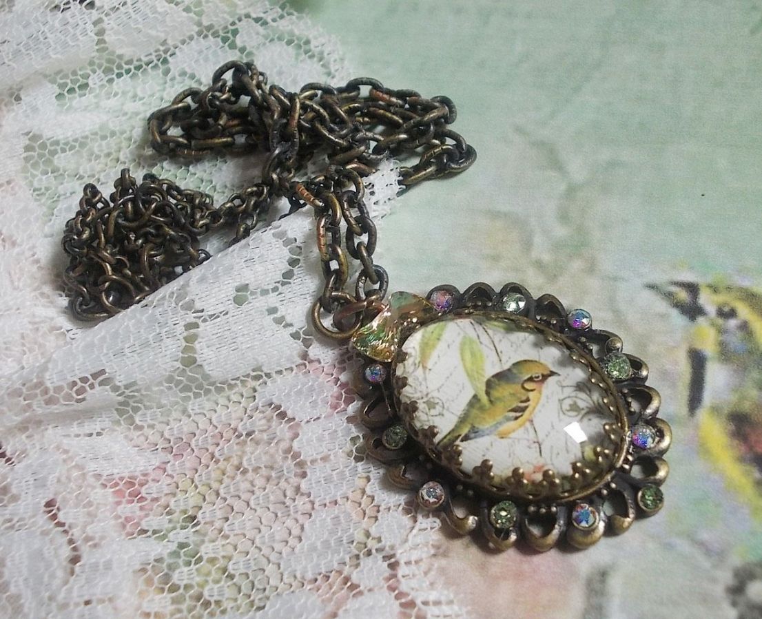 Bird of the Gardens necklace created with a magnifying glass cabochon and crystals mounted on bronze accessories