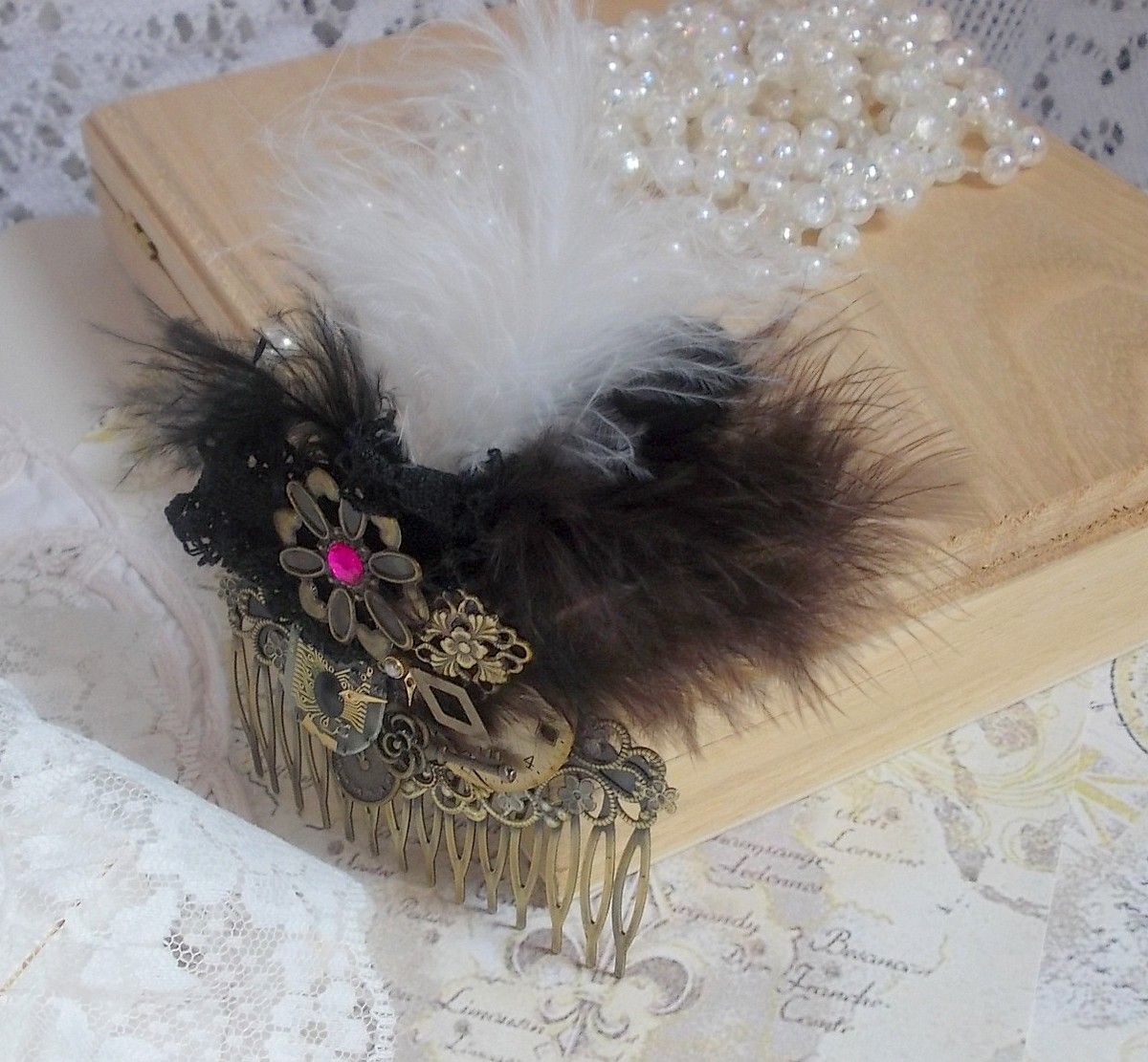 Curiosity Time hair comb created with black lace, various accessories, charms of gold, silver, bronze colors with black, brown and white feathers