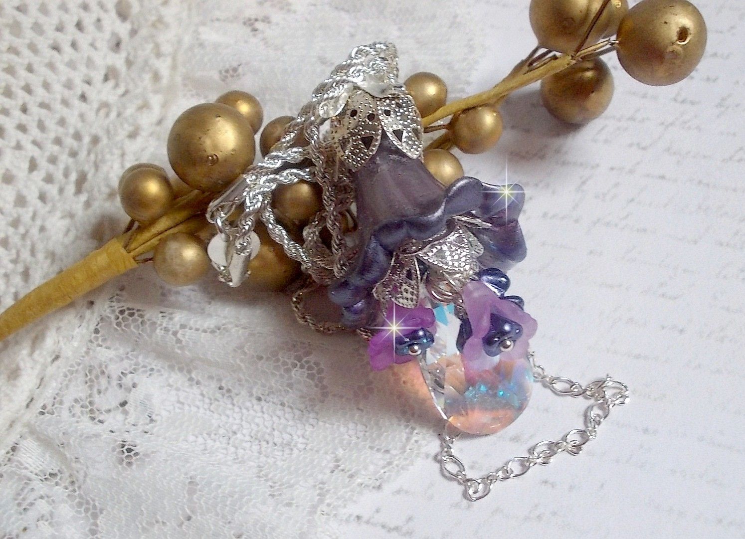 Pendentif Eclat de Cristal monté avec une goutte en Cristal, fleurs en Verre, fleurs lucites dont une plus grande peinte à la main avec paillettes Argentées. Une composition florale