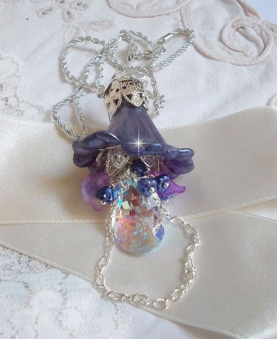 Pendentif Eclat de Cristal monté avec une goutte en Cristal, fleurs en Verre, fleurs lucites dont une plus grande peinte à la main avec paillettes Argentées. Une composition florale