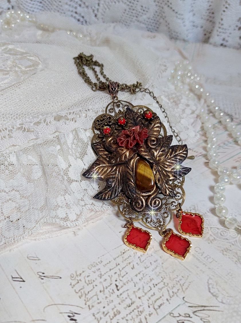 Pendentif Mélodie avec un cabochon Œil de tigre orné de perles en Jade Rouge veiné de Noir sur fleurs 5 pétales et estampes montés sur une chaîne bronze. Les pendants sont en résine époxy Rouge