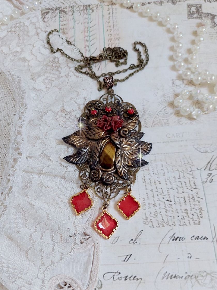 Pendentif Mélodie avec un cabochon Œil de tigre orné de perles en Jade Rouge veiné de Noir sur fleurs 5 pétales et estampes montés sur une chaîne bronze. Les pendants sont en résine époxy Rouge