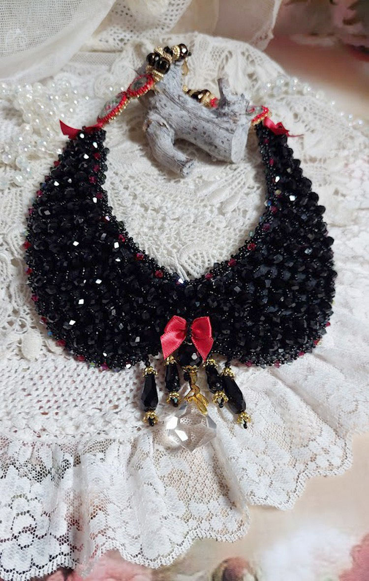 Plastron Nuit d’Etoiles brodé avec toupies, poire facettée en Cristal, perles rondes aplaties, perles potirons, estampes, cabochons, nœud, strass, rondelles avec une chaînette et un fermoir plaqué or